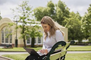 A girl sitting in a park using laptop